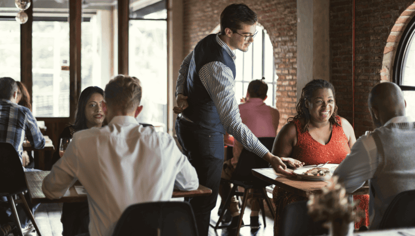 A waiter serving food to hearing impaired people at a restaurant